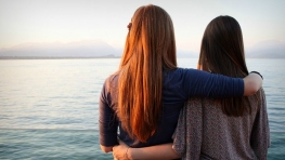 δύο γυναίκες αγκαλιασμένες κοιτούν τη θάλασσα