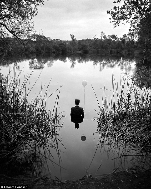 άντρας με κουστούμι μέσα σε μια λίμνη κρατάει ένα μπαλόνι