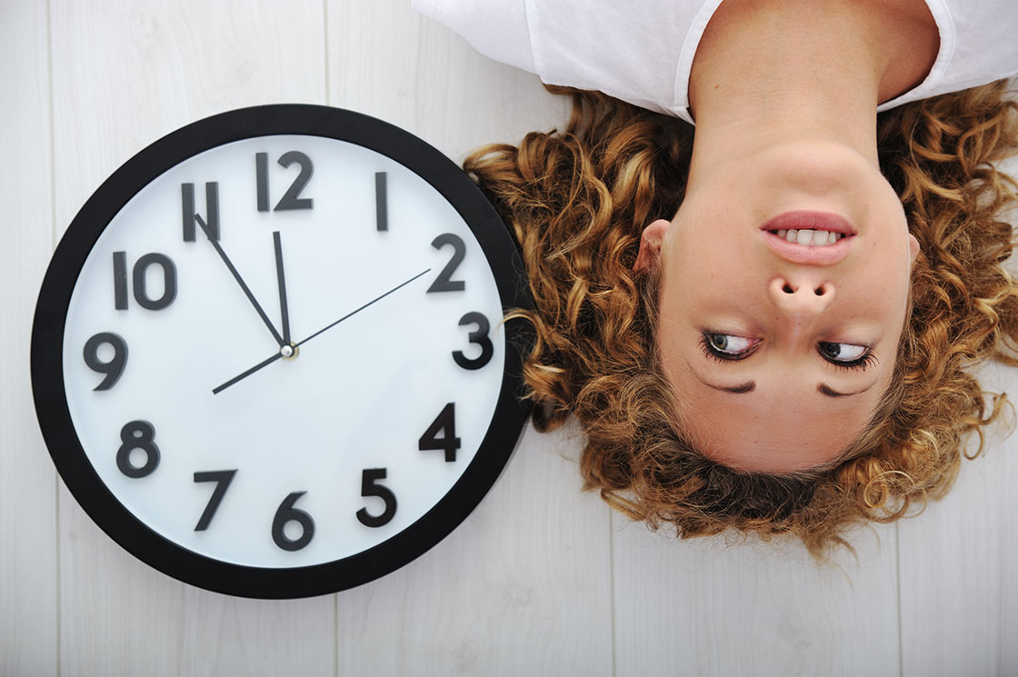 γυναίκα ξαπλωμένη με ένα ρολόι δίπλα στο κεφάλι της