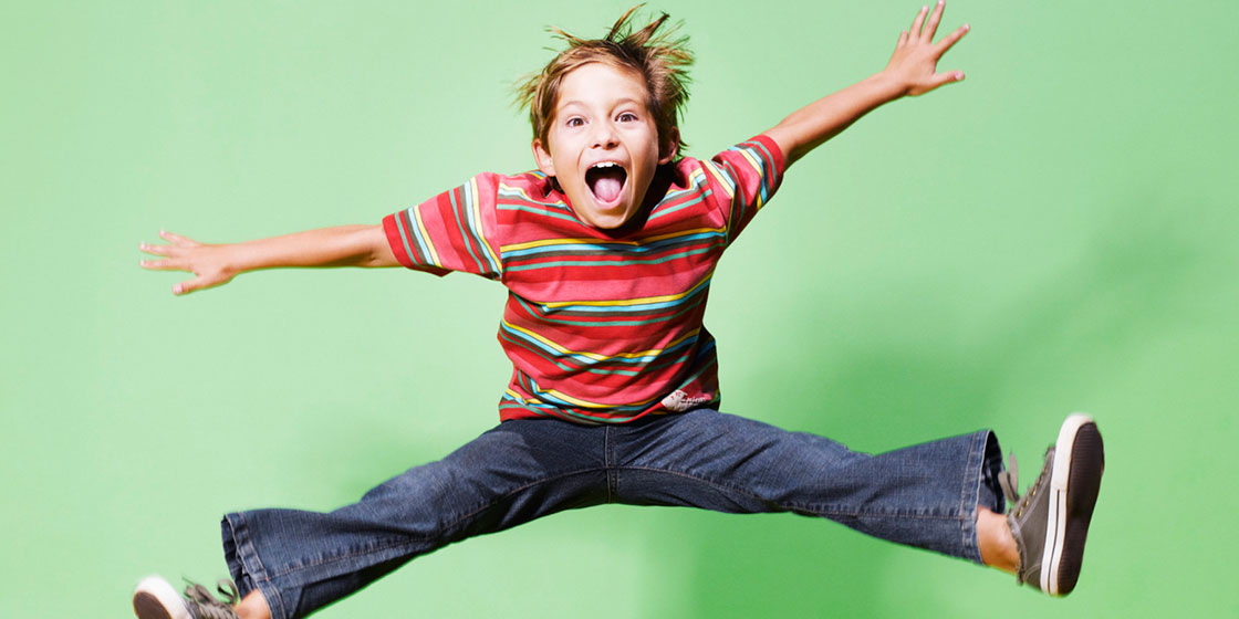 χαρούμενο παιδί πηδά στο αέρα με τα πόδια ανοιχτά