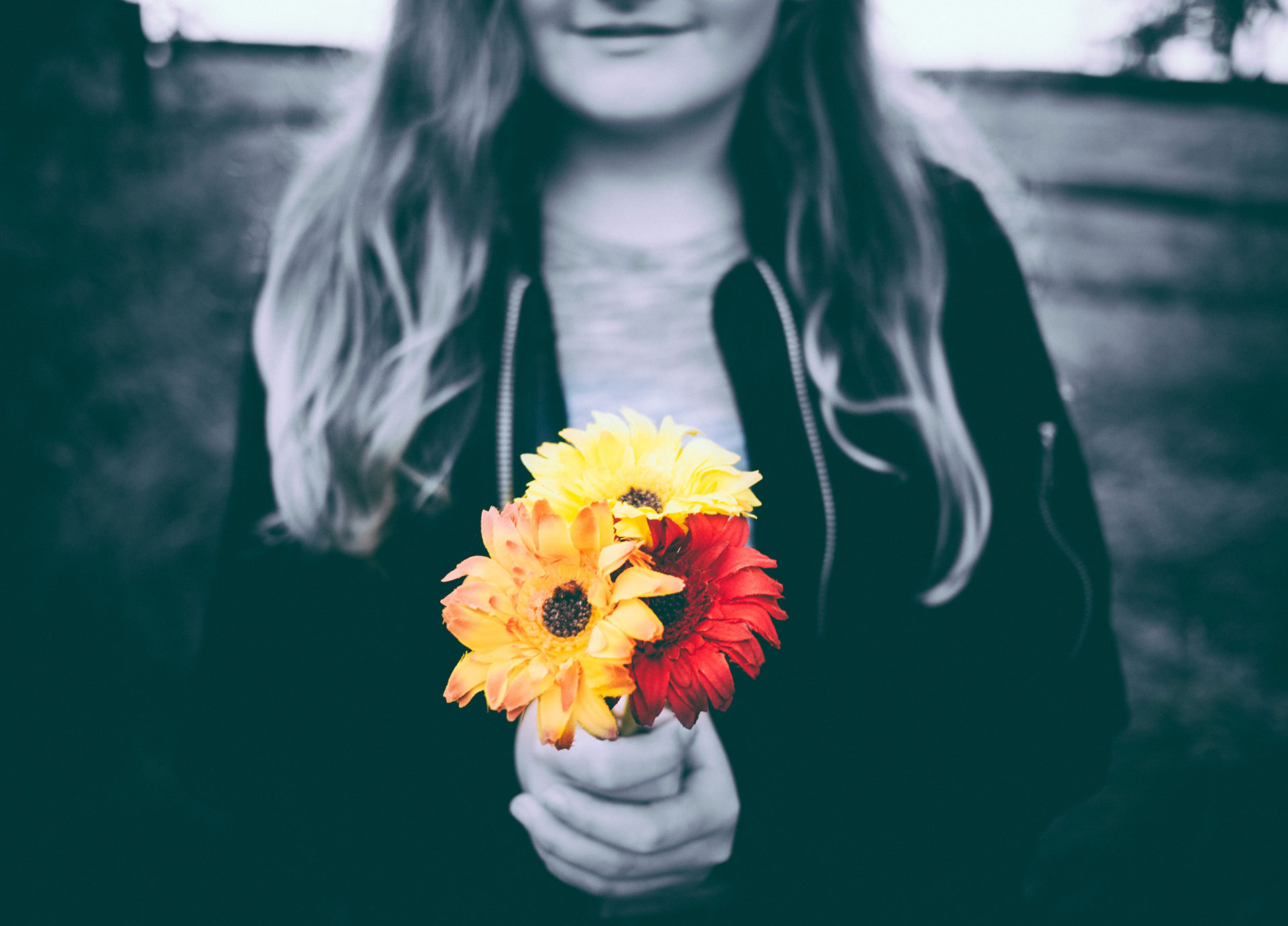γυναίκα με διαταραχή προσωπικότητας σε ασπρόμαυρο φόντο κρατάει ένα κόκκινο και ένα κίτρινο λουλούδι
