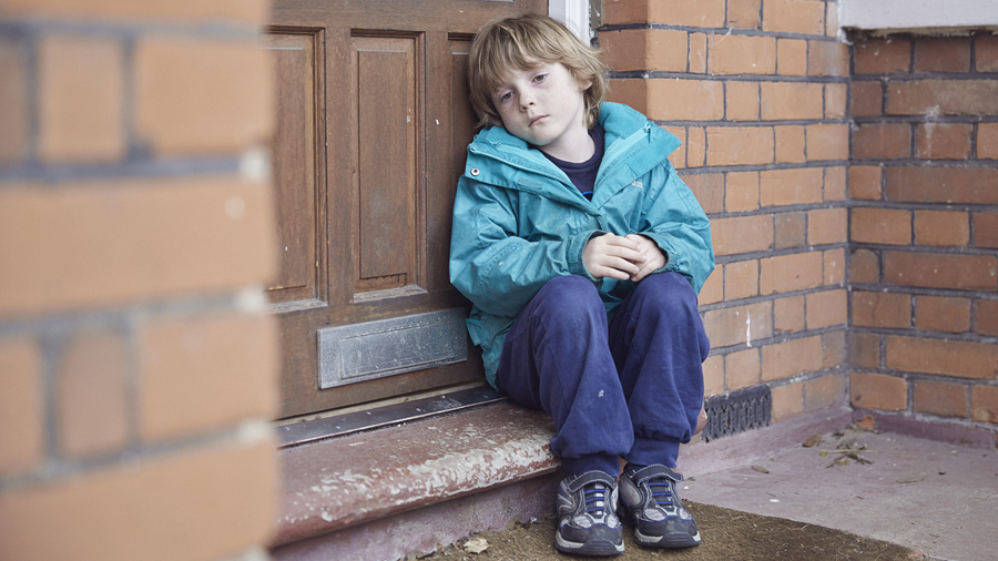 παιδί που κάθεται μόνο και στεναχωρημένο με ψυχική ασθένεια στο σκαλί μίας πόρτας