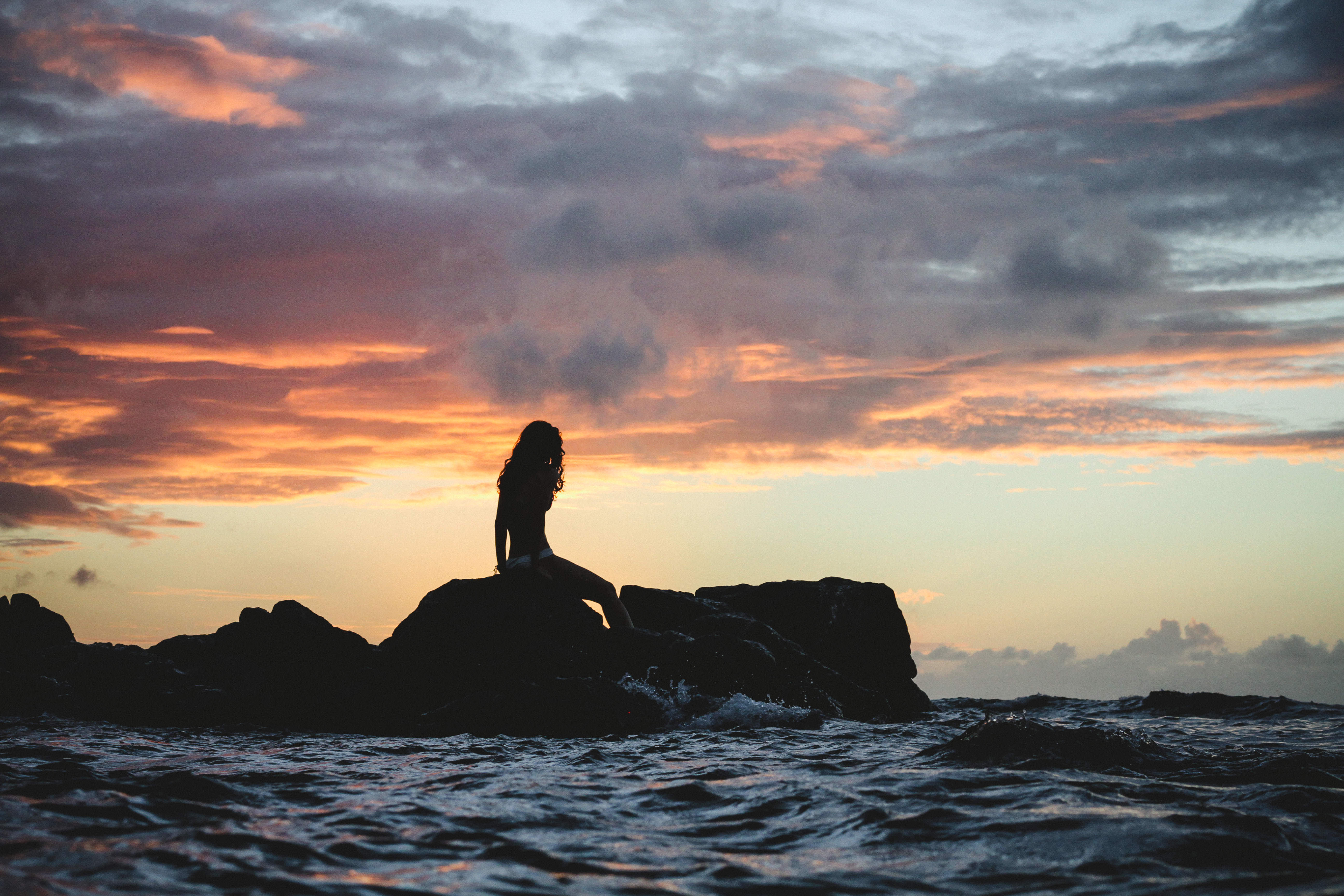 μια γυναίκα κάθεται σε ένα βράχο στη θάλασσα