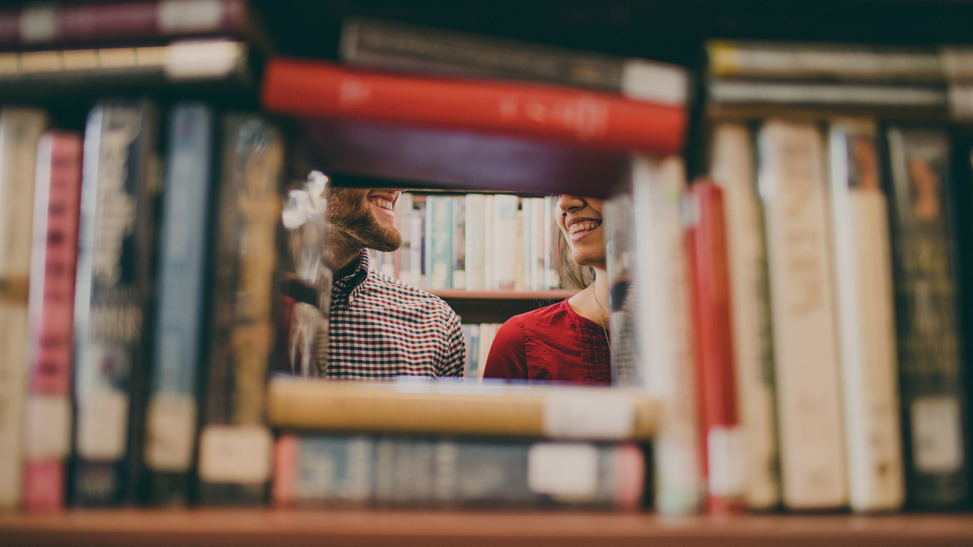 δύο άτομα κρυμμένα πίσω από μια βιβλιοθήκη