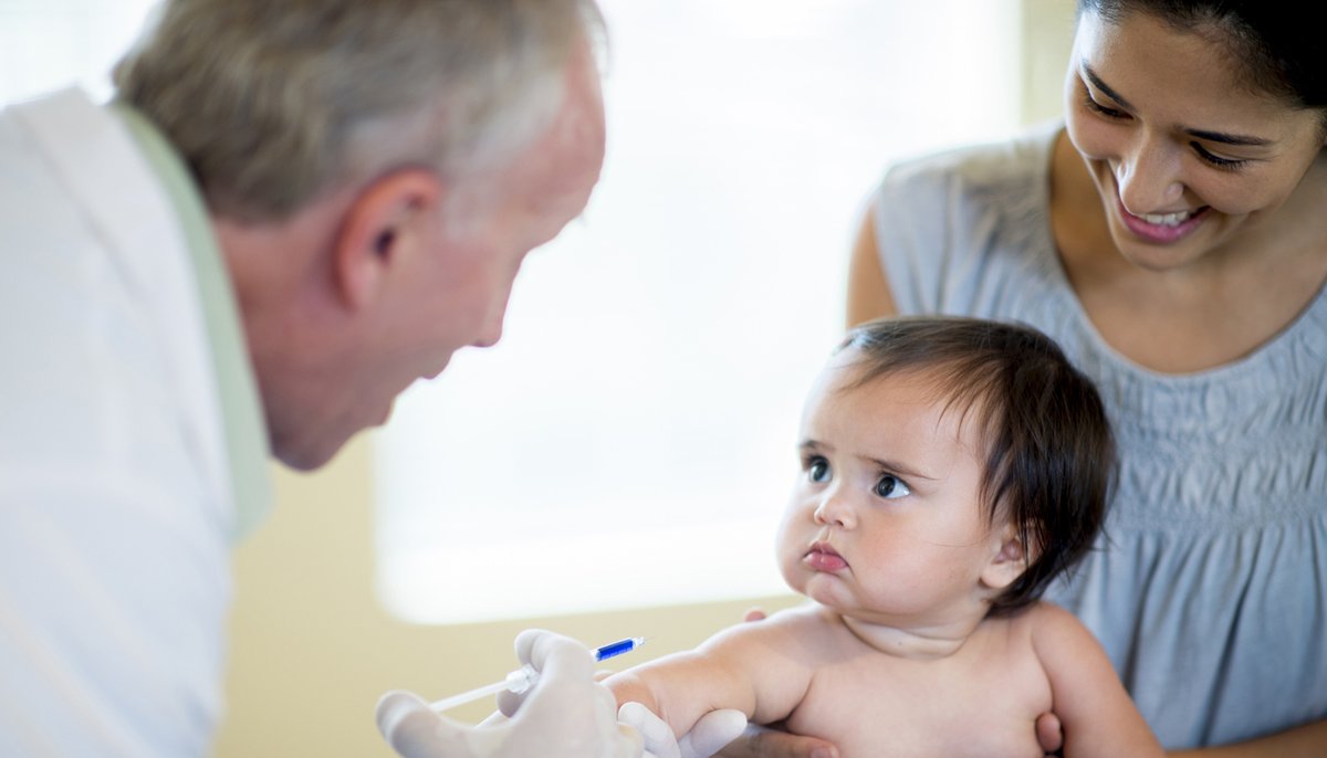 παιδί κοιτάει τον γιατρό ενώ δέχεται εμβόλιο