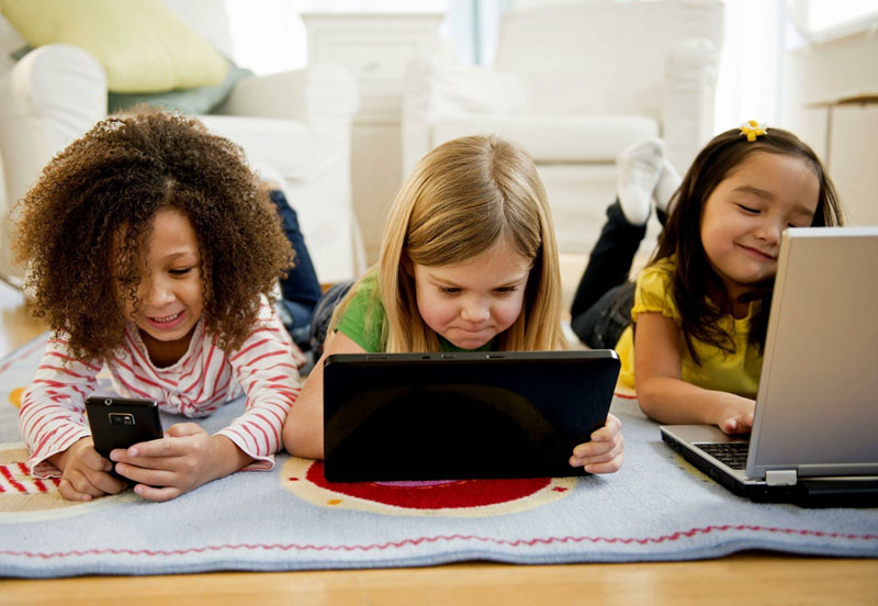 3 κοριτσάκια μπροστά από διάφορες ηλεκτρονικές συσκευές