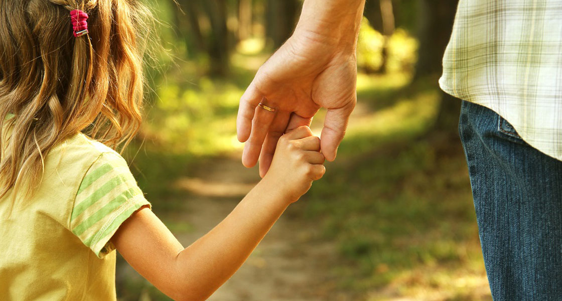 γονέας που δίνει το χέρι του σε ένα κοριτσάκι μέσα σε δάσος