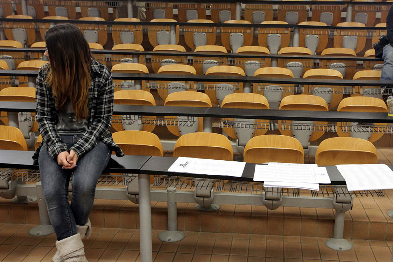 φοιτήτρια κάθεται πάνω σε θρανίο πανεπιστημίου