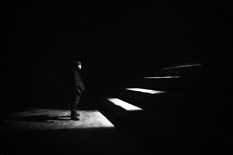 άνθρωπος στέκεται στο τέλος των σκαλοπατιών σε ένα σκοτεινό δωμάτιο