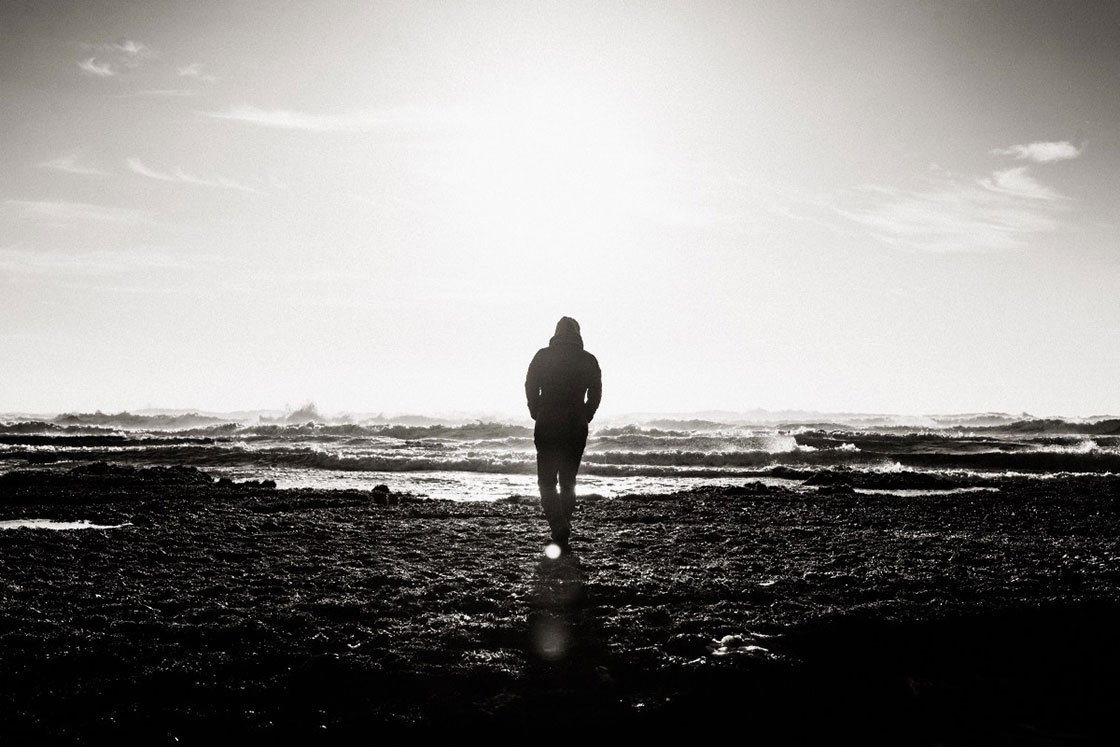 άνδρας μόνο σε ασπρόμαυρη εικόνα να περπατάει στη θάλασσα