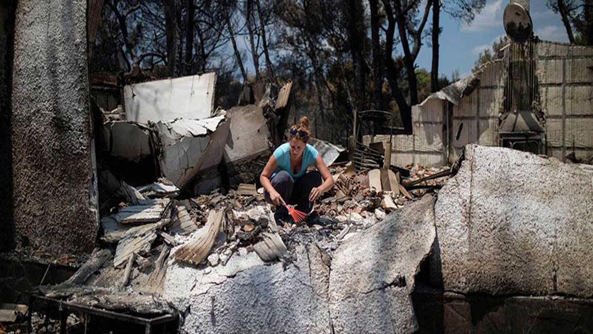 γυναίκα σε κατεστραμμένο σπίτι ψάχνει τα συντρίμμια